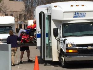 Person in wheelchair boarding paratransit van with lift