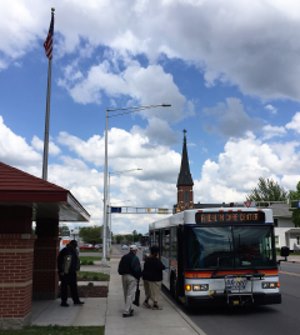 American Flag next to a bus at a bus stop picking up people.